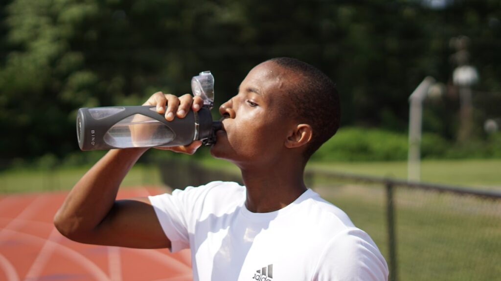 Athlete drinking water to stay hydrated while exercising in the heat