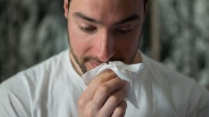 Man with seasonal allergy symptoms blowing his nose
