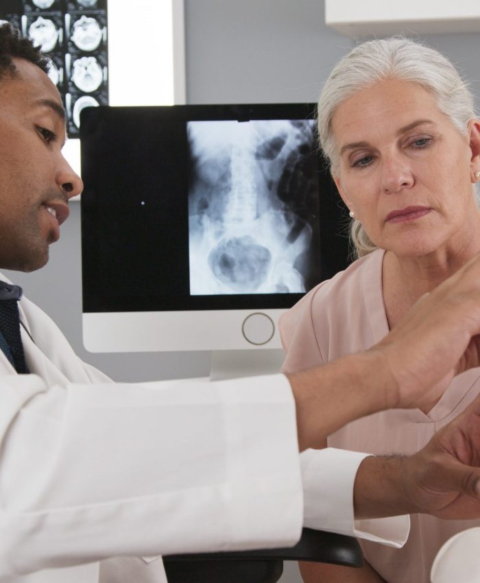Senior female patient consulting with young doctor about back injury